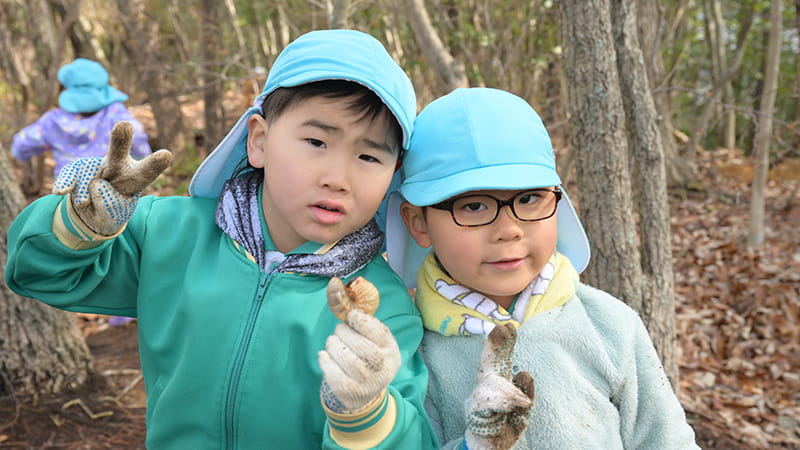昆虫の幼虫をてにもったこどもたち